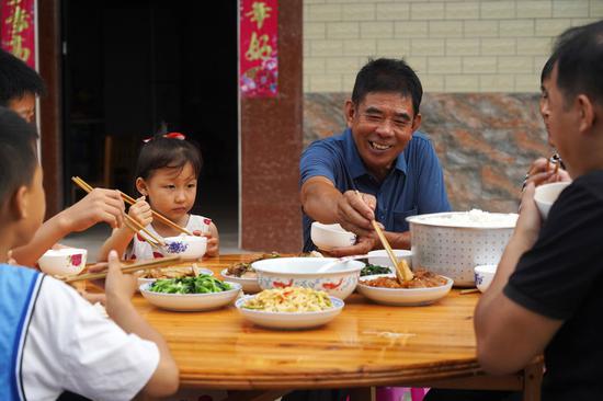 ↑2021年7月1日，江西省瑞金市叶坪镇禾仓村村民曾得涛（中）和家人一起吃早饭。