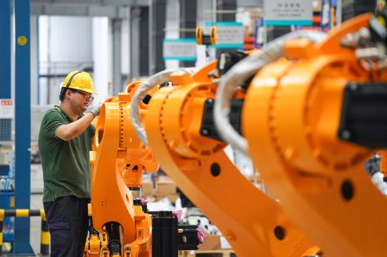  ↑2021年7月1日，在位于南京市江宁区的南京埃斯顿自动化股份有限公司工业机器人生产车间，工作人员对组装好的工业机器人进行调试。