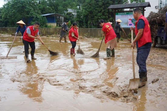 2022年6月21日，在江西省德兴市泗洲镇张家畈社区，党员干部在清理淤泥和垃圾。新华社记者 周密 摄