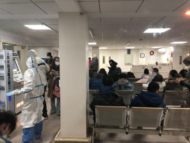 2022年12月12日晚，北京朝阳医院发热门诊分诊区坐满了患者，工作人员在一旁维持秩序。《财经》记者 金贻龙/摄